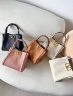 شنطة نسائية صغيرة فاخرة جلد مع لوقو ذهبي – تصميم أنيق بيد علوية وألوان متعددة